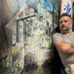Artist stands next to one of his paintings